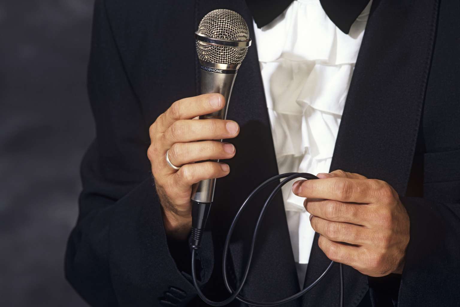 Conferencier in elegant suit holding the microphone